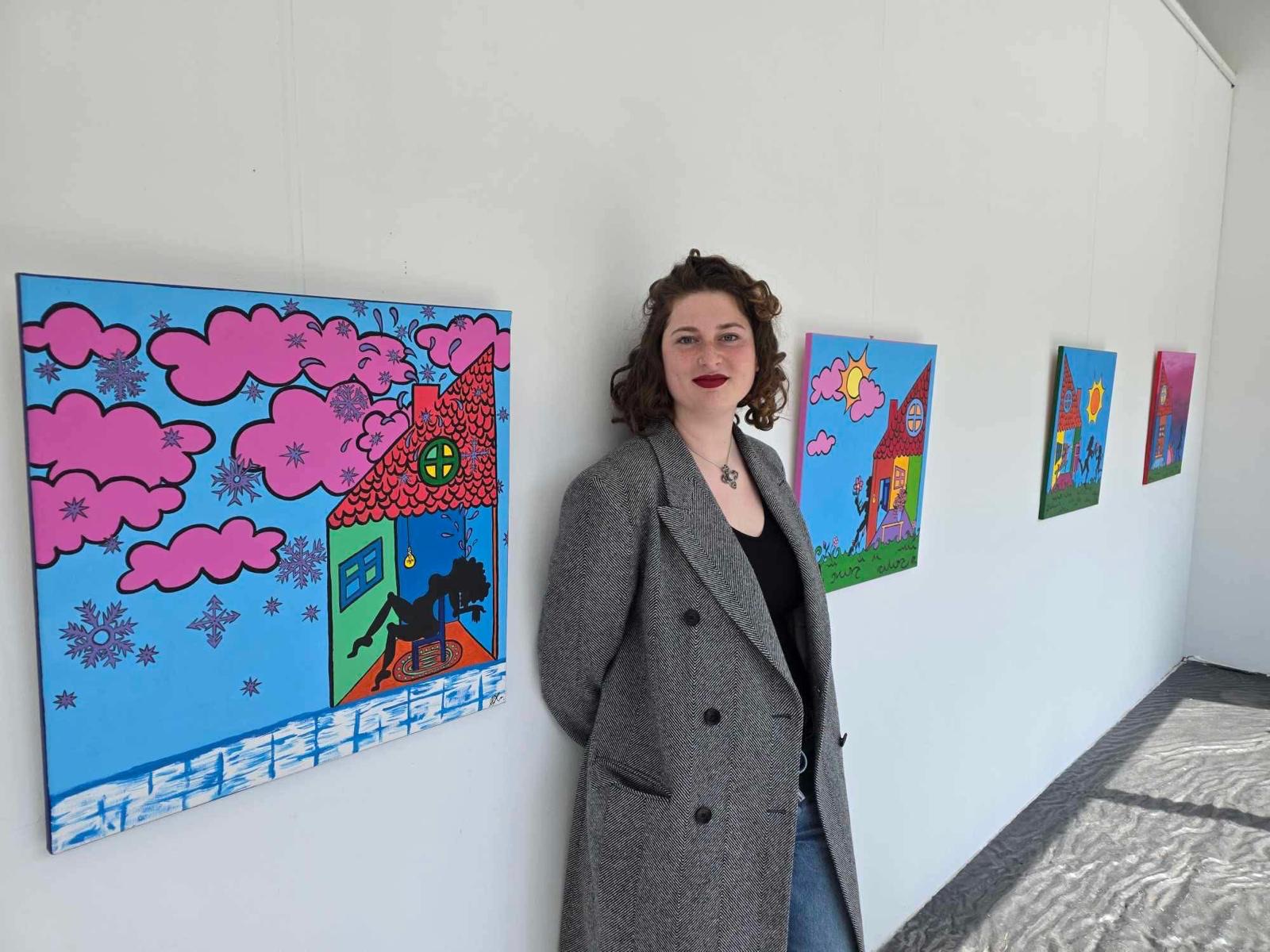 Maria Papatheodorou beside her acrylic paintings at an exhibition