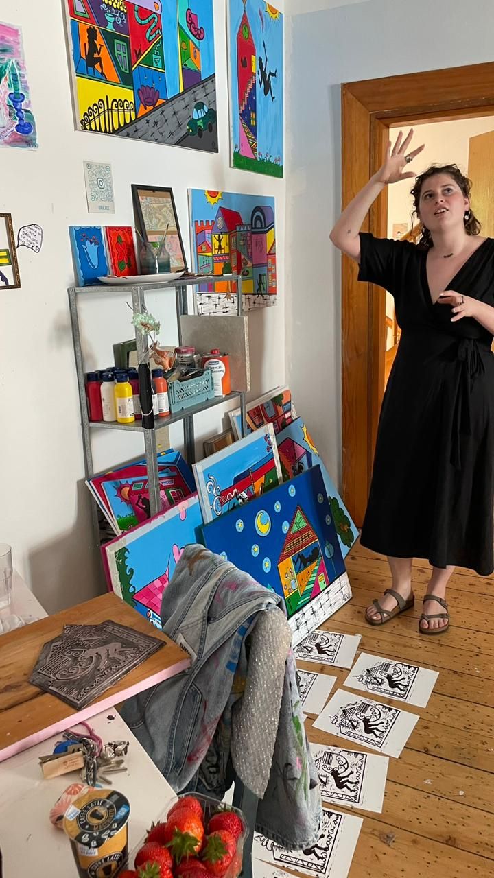 Maria in the studio, linocuts drying on the floor and paintings stacked against the wall